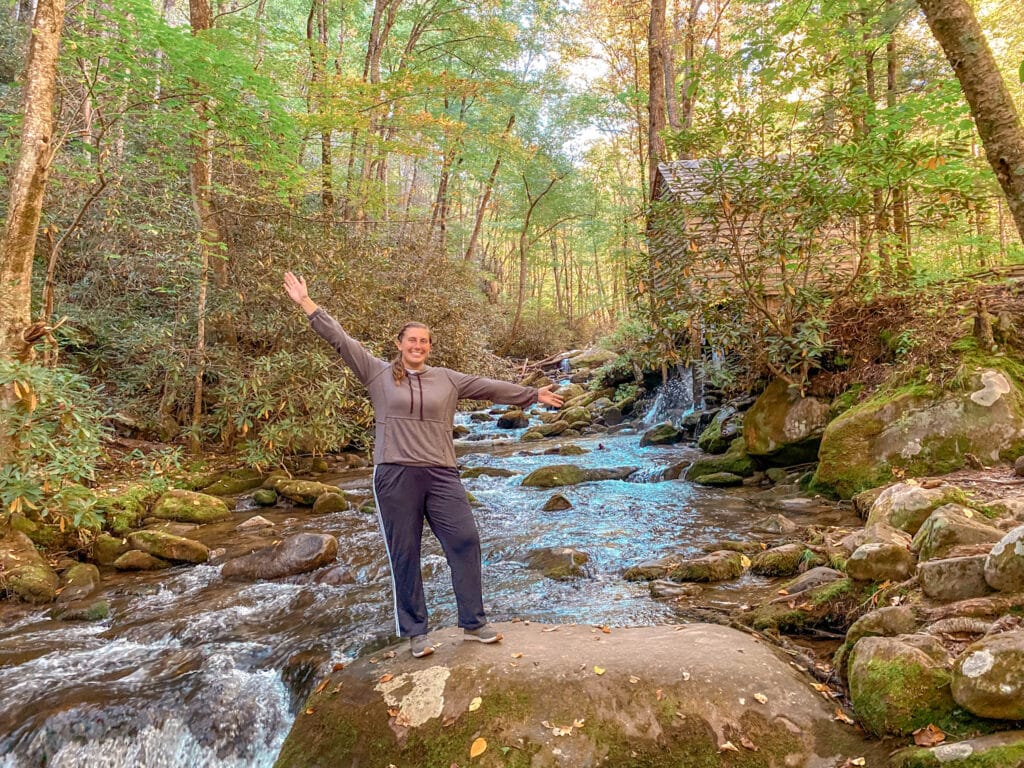 woman standing on rock with stream in background Smoky Mountains
