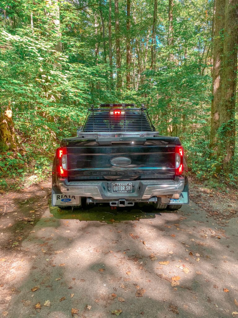 Large black ford truck driving through smoky mountain forest