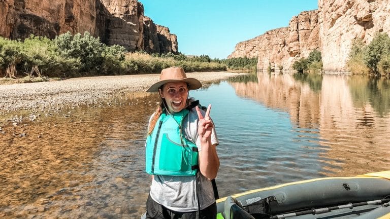 Woman giving a peace sign in front of river
