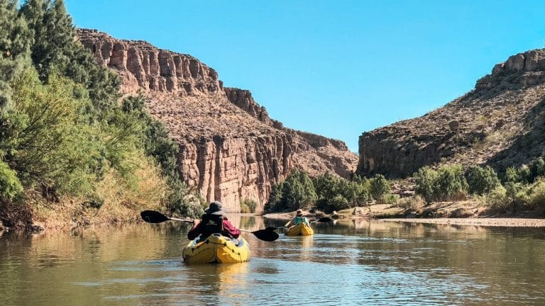 Two kayakers floating on the Rio Grande river.