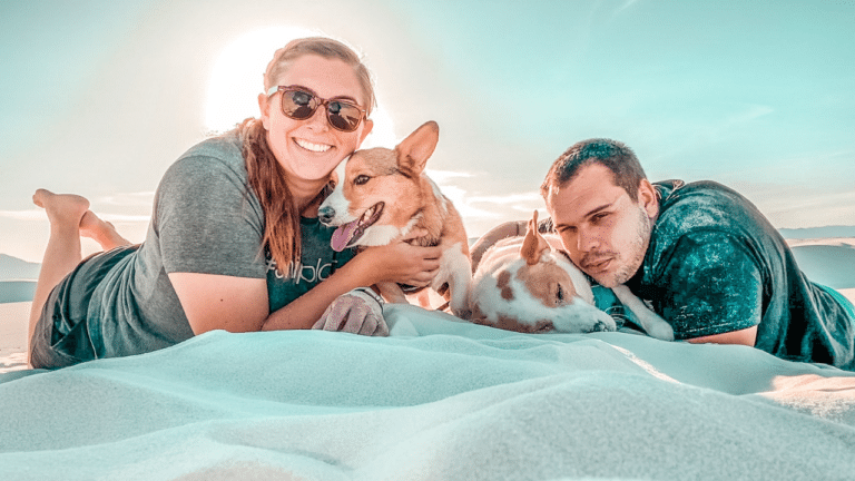 Family laying in the sand at a national park with their dogs.