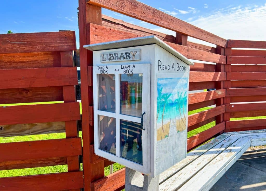 Isla Blanca RV Park little free library in front of red painted wooden fence