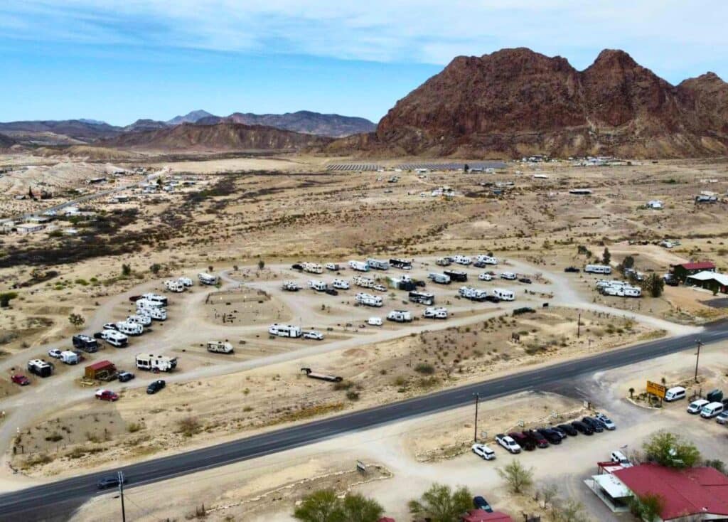 Overhead drone picture of the RoadRunner Travelers RV Park. Desert and mountains are situated behind the RV park.