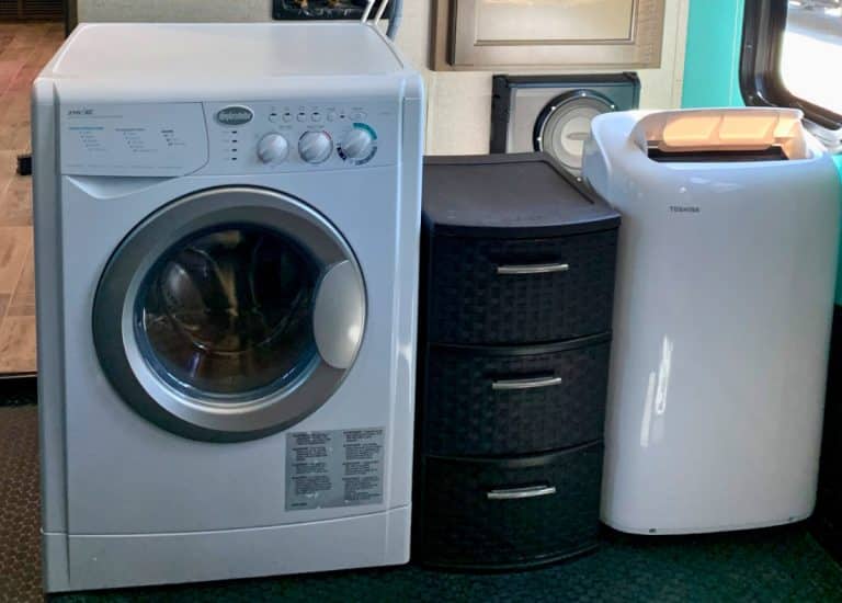 RV washer dryer combo is on the left with a brown storage container drawers next to it. On the right side of the storage drawers is a portable AC unit.