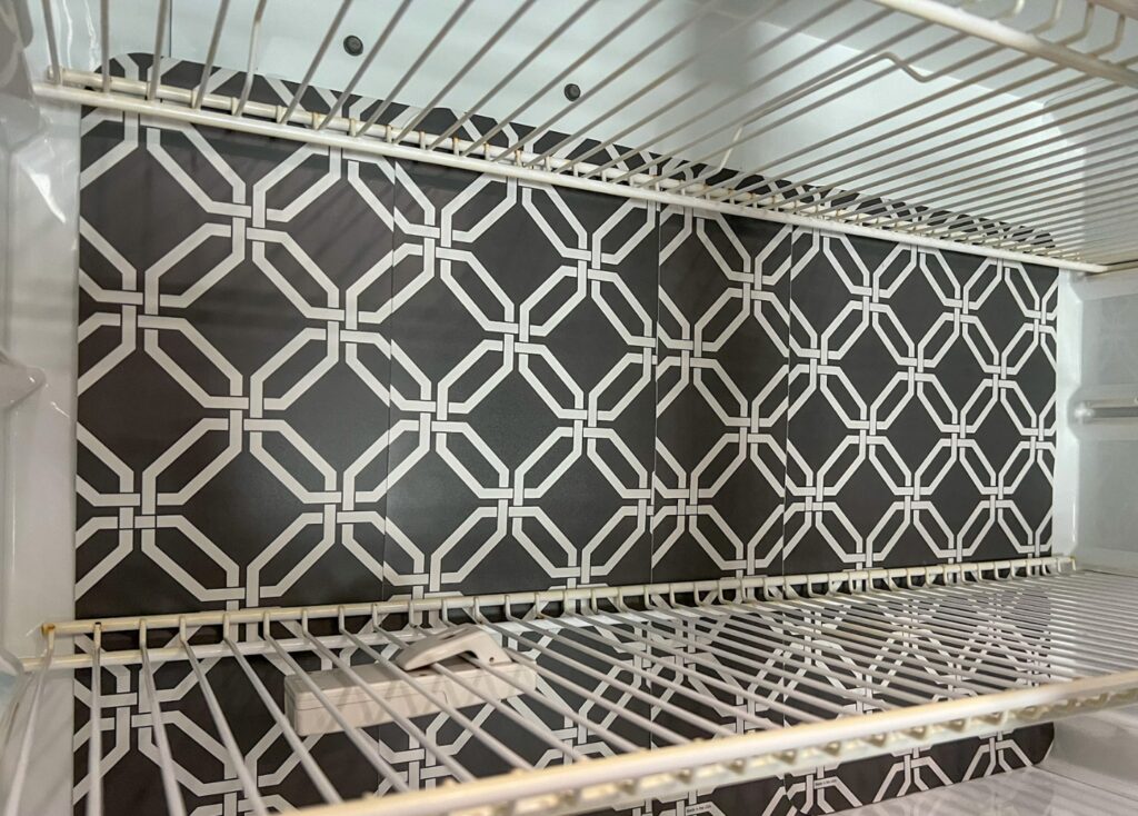 Dark grey placemats with a geometric white pattern are lined up against the back of the freezer. The wire racks inside the freezer hold them in place.