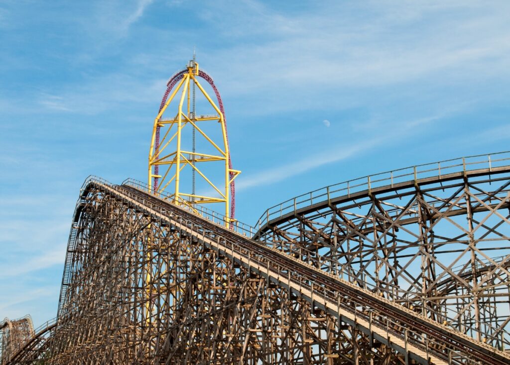 Wooden roller coaster, Gemini, stands in front of Top Thrill Dragster roller coaster on a sunny day at Cedar Point.