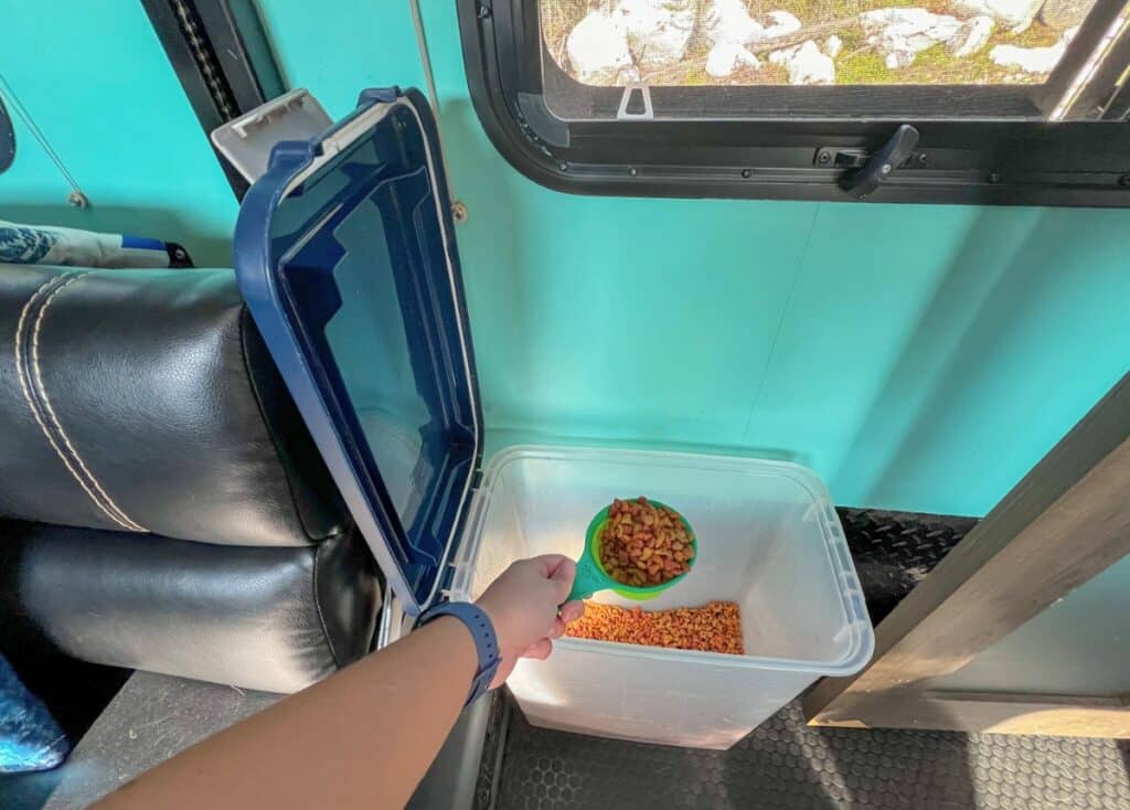 A scooping food out of an air tight dog food storage container inside an RV.