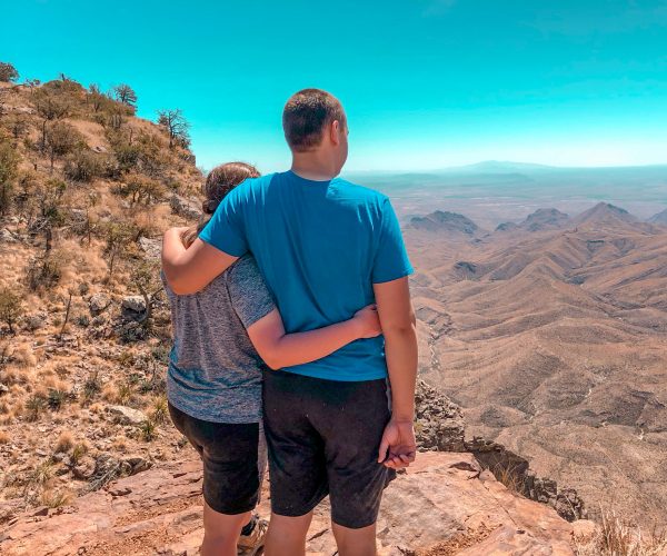 Couple standing side by side with their arm around each other overlooking the desert views from the South Rim Trail.