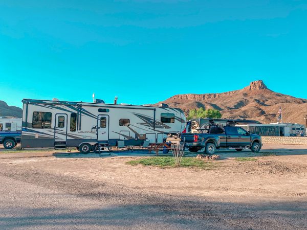 A white fifth wheel and black Ford F-350 are parked at Maverick Ranch RV Park in campsite 79 with Lajitas Mesa in background. 