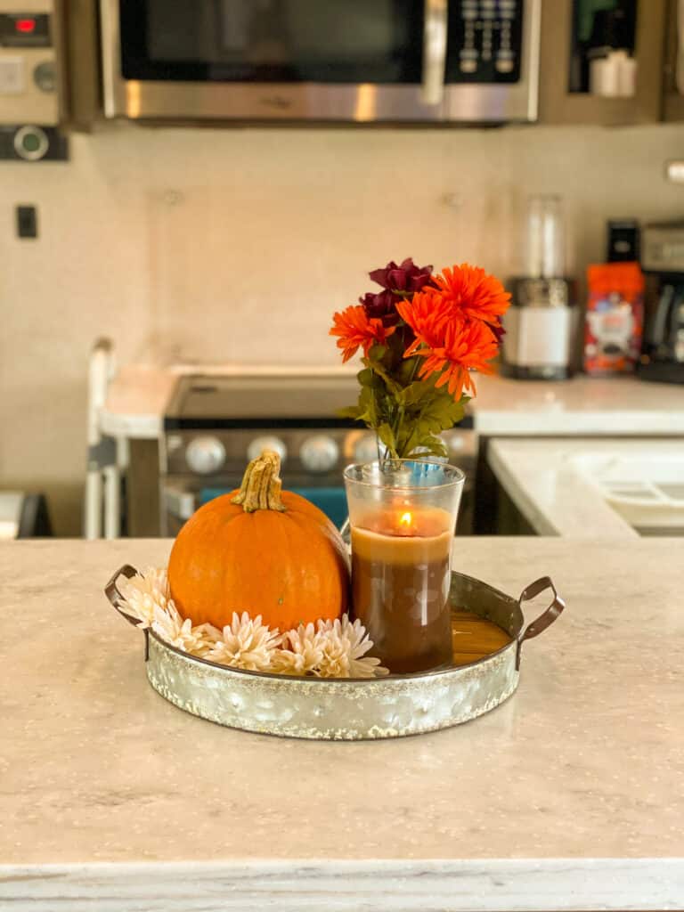 Pumpkin, candle and flowers on decor tray