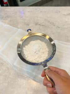 sprinkling powdered sugar on cloth
