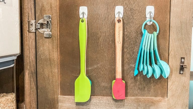 Command hooks inside cabinet holding measure spoons and spatulas