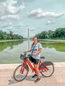 Woman on bike in front of reflection pool Washington monument in distance