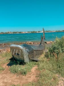 metal shark statue in front of lake