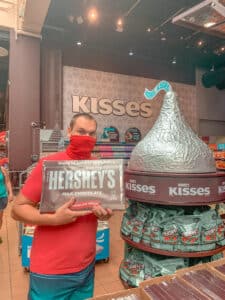 man holding giant Hershey's chocolate bar inside Hershey's Chocolate World