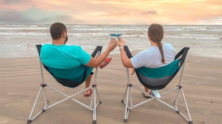 couple sitting on the beach in hammock chairs
