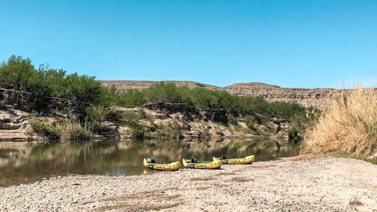 Three yellow kayaks sitting on banks of the Rio Grande river in Big Bend.