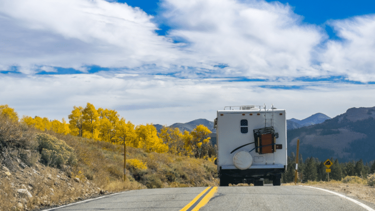 Travel trailer driving down a two lane road with mountains ahead