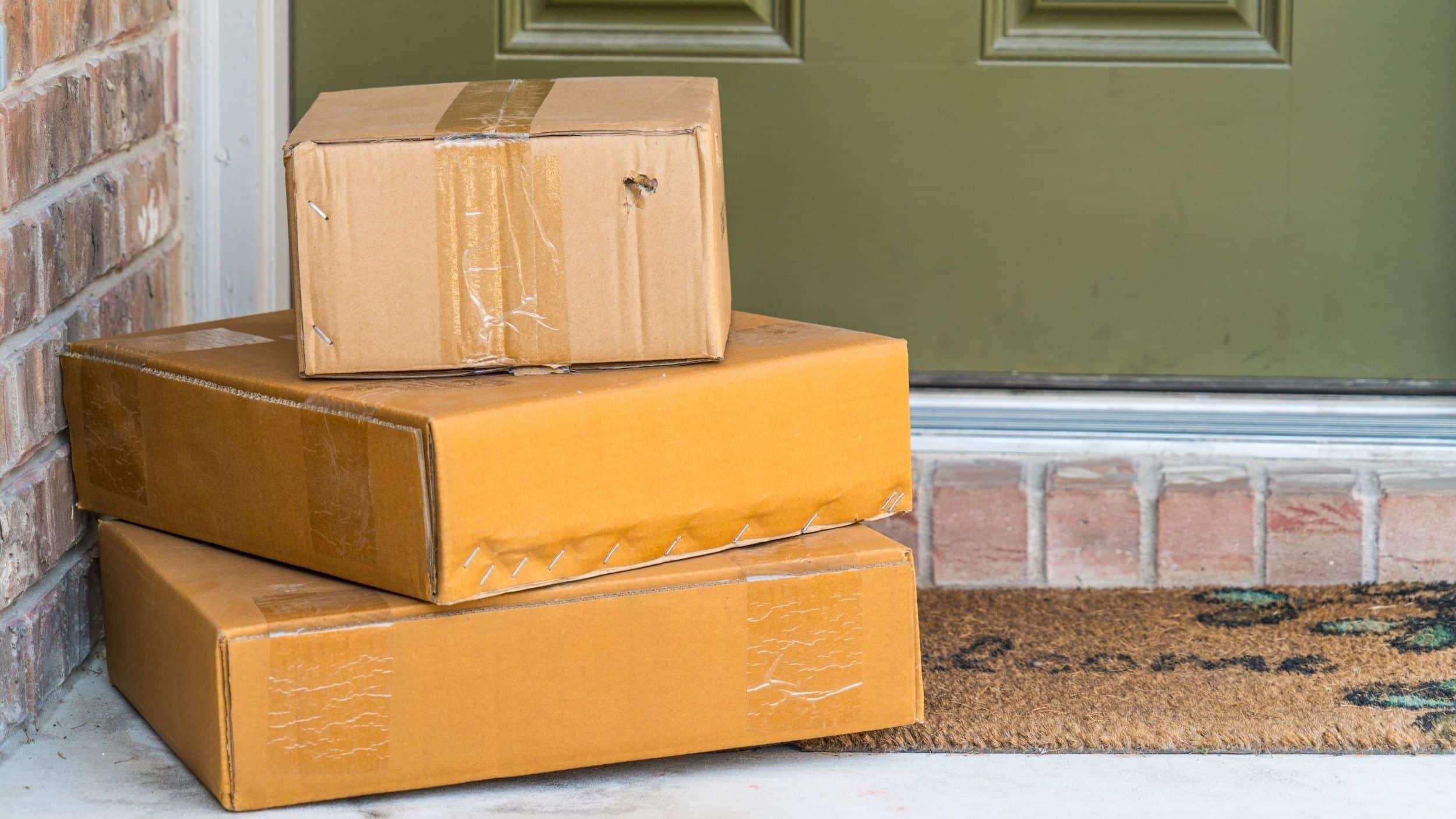 3 boxes stacked on each other sitting on porch in front of a green front door.