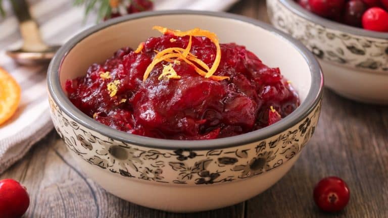 Bowl of cranberry sauce on table topped with orange peel