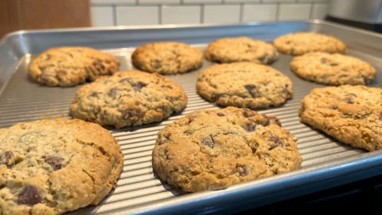 Metal sheet pan with row of oatmeal chocolate cookies lined up